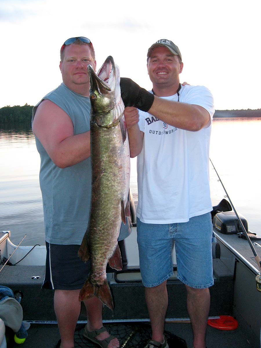 Two men holding up a musky they just caught off their boat