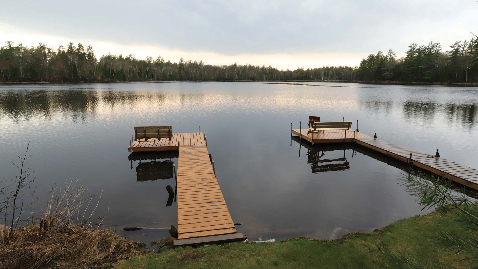 Two docks overlooking an empty lake, surrounded by trees